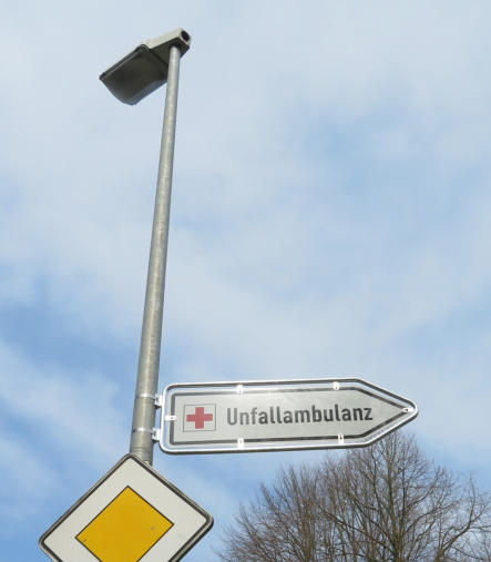 Krankenhaus-Wegweiser mit Rohrrahmen, am Pfosten befestigt mit Bandschellen